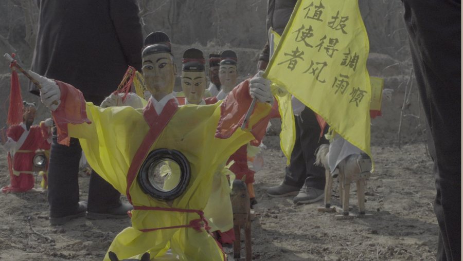 醮仪中使用的纸扎「值使者」，手持黄旗，旗上写「报得调风雨顺」，旁边是纸马（梁君健摄，取自课件）。这是要把信众的表文送上天的使者。